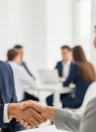 Ein Bewerber schüttelt im zweiten Vorstellungsgespräch einem Personaler selbstsicher die Hand.