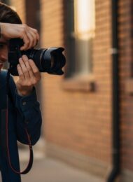 Ein Fotograf macht ein Porträtfoto einer lachenden Frau - Grundlagen der Porträtfotografie erklärt.