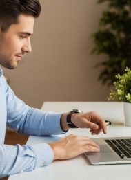 Ein Mann schickt seine erfolgreiche Online-Bewerbung von seinem Laptop ab.