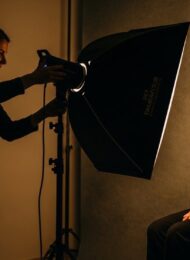 Eine Fotografin bei der professionellen Lichtsetzung für ein Porträtfoto im Studio.