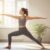 Eine Frau praktiziert eine Yoga-Übung in ihrem sonnigen Wohnzimmer.