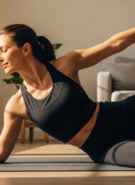 Eine Frau stärkt mit einer Pilates-Übung auf einer Matte gezielt ihren Rücken.