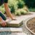 Eine Person legt einen Gartenweg mit Natursteinplatten in einem blühenden Garten an.